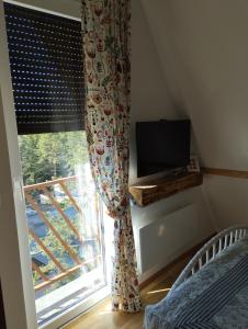 Un dormitorio con una cama y una ventana con televisión. en Tajna, en Divčibare