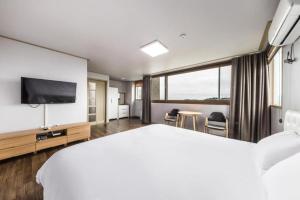 a hotel room with a bed and a flat screen tv at Orange Hotel Jeju in Seogwipo