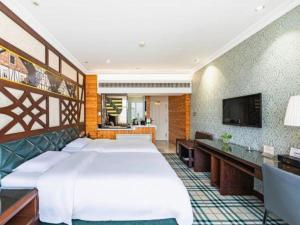 a hotel room with a bed and a flat screen tv at Zaozhuang Hotel in Zaozhuang