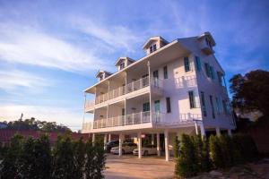 un grand bâtiment blanc avec des voitures garées dans un parking dans l'établissement The Prince Hotel, à Campson