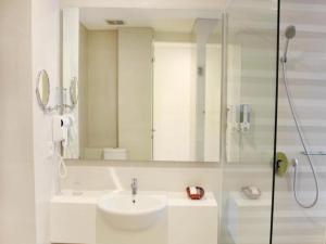 a white bathroom with a sink and a shower at Everbright Ambon Hotel in Ambon