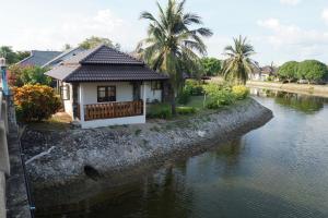 a small house next to a river with palm trees at Rock Garden E28 4 bedroom Pool villa in Mae Pim