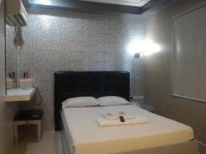 マニラにあるJardin de Rosal Hotelの小さなベッドルーム(黒いヘッドボード付きのベッド1台付)