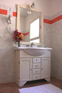 uma casa de banho com um lavatório branco e um espelho. em Hotel Pedra Ruja em Budoni