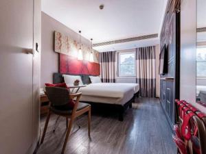 een hotelkamer met een bed, een bureau en een stoel bij Ibis Ya An Langqiao in Shaping +119 foto's