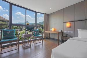 a bedroom with a bed and chairs and a large window at Chengdu Nine Point Art Hotel in Chengdu +242 photos