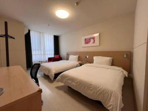 pokój hotelowy z dwoma łóżkami i biurkiem w obiekcie Jinjiang Inn Tianjin Jizhou Renmin West Street Branch w mieście Jixian +113 zdjęć