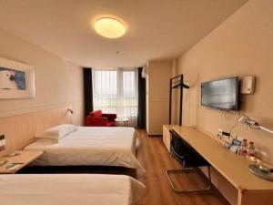 pokój hotelowy z dwoma łóżkami i telewizorem z płaskim ekranem w obiekcie Jinjiang Inn Tianjin Jizhou Renmin West Street Branch w mieście Jixian