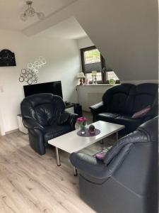 a living room with two leather chairs and a table at Ostfrieslandsuite in Aurich