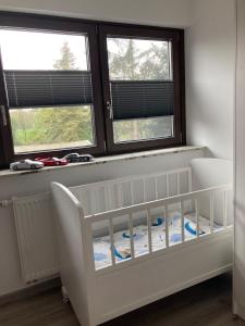 a white crib in a room with two windows at Ostfrieslandsuite in Aurich +17 photos