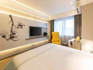a hotel room with a bed and a tv at Magnotel Fuzhou Wuyi Road Sanfangqixiang in Fuzhou