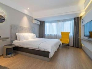 a bedroom with a bed and a yellow chair at Magnotel Fuzhou Wuyi Road Sanfangqixiang in Fuzhou