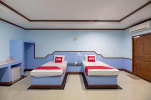 two beds in a room with blue walls and red pillows at OYO 75334 Train Hotel in Ban Don Rak