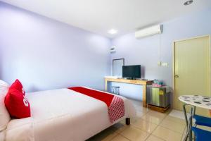 a bedroom with a bed and a desk with a television at OYO 981 Fluke and Flame Cha Am in Cha Am
