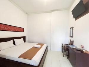 a white bedroom with a bed and a desk at Indonesia Hotel Malioboro in Yogyakarta