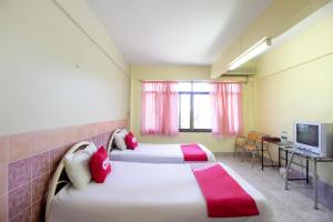 a hotel room with two beds and a television at OYO 75372 Flight hut hotel in Hua Hin