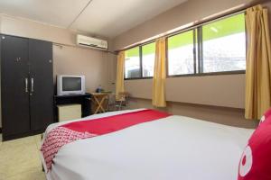 a bedroom with a bed and a tv and windows at OYO 75372 Flight hut hotel in Hua Hin