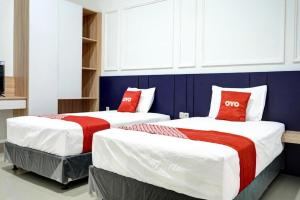 two beds with red pillows in a room at Capital O 92804 La Tansa Syariah Hotel in Bekasi