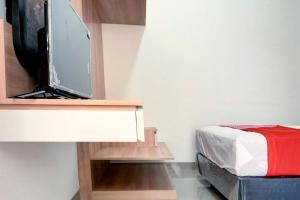 a bedroom with a bed and a flat screen tv at Capital O 92804 La Tansa Syariah Hotel in Bekasi