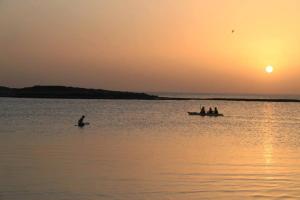 um grupo de pessoas em um barco na água ao pôr do sol em Dor Country Lodging em Dor