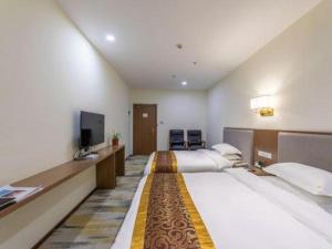 a hotel room with two beds and a flat screen tv at Jinggangshan Edenplaza Hotel in Jinggangshanzonghekenzhichang