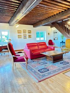 a living room with a red couch and a table at Séjourner au Château de la Roue Grand appartement in Lissieu