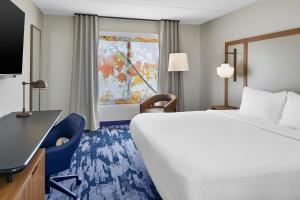 a hotel room with a bed and a desk and a window at Fairfield Inn by Marriott Rochester East in Webster +21 photos