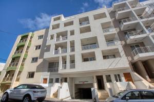 a building with two cars parked in front of it at New! Spacious 4-Bedroom Duplex apartment by SF Homes in Tal-Ħriereb