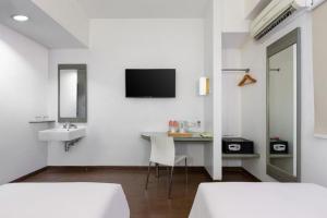a white room with a desk and a sink and a tv at Amaris Hotel Padjajaran Bogor in Bogor