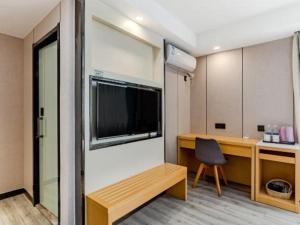 a room with a desk and a television and a chair at GreenTree Alliance Jiangsu Nanjing Pukou District Zhongsheng Street Wende Road Metro Station Hotel in Pukou