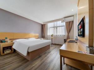 a bedroom with a large bed and a desk at GreenTree Inn Nantong Zhangzhishan Town Deli Plaza Express Hotel in Nantong
