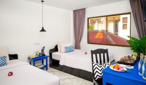 a room with two beds and a couch and a window at Popular Hotel & Spa in Siem Reap