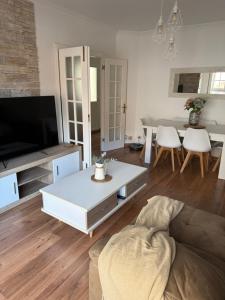 a living room with a couch and a tv and a table at Piso Praia da Rocha in Serres