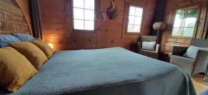 a bedroom with a bed with blue sheets and windows at chalet bois pleine campagne à Pontigny in Pontigny