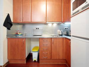 a kitchen with wooden cabinets and a white refrigerator at Olles Apartment in Barcelona