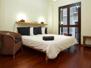 a bedroom with a bed and a chair and a window at Olles Apartment in Barcelona