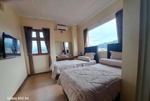 ein Hotelzimmer mit zwei Betten und einem Fernseher in der Unterkunft Cipada Guesthouse syariah in Sumedang