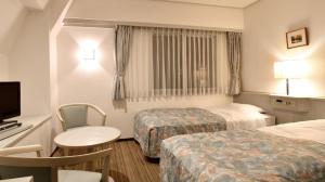 a hotel room with two beds and a television at City Park Hotel Hachinohe in Minatomachi
