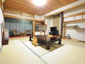 Una sala de estar con una mesa y un televisor. en Hotel Gomi, en Shinryū