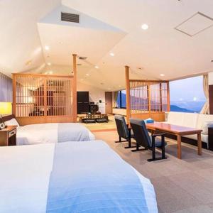 a bedroom with two beds and a table with chairs at South Aso and Relaxing Spa Resort Hotel Greenpia Minamiaso in Aso
