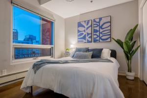 a bedroom with a bed and a large window at Downtown Chic Retreat | Elegant + Free Parking in Calgary