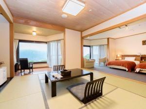 a bedroom with a bed and a living room with a table at South Aso and Relaxing Spa Resort Hotel Greenpia Minamiaso in Aso