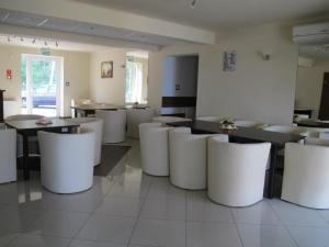 un restaurante con mesas blancas y sillas blancas en Przystań Wodna Brody en Styków