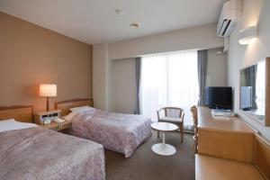 a hotel room with two beds and a television at Hotel Tenchikaku in Hitachi