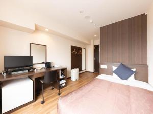 a bedroom with a bed and a desk with a computer at Tabist City Hotel Higashi-Matsuyama in Higashimatsuyama