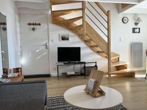 sala de estar con TV y escalera en Duplex rénové avec vue exceptionnelle sur le port d’Erquy, en Erquy