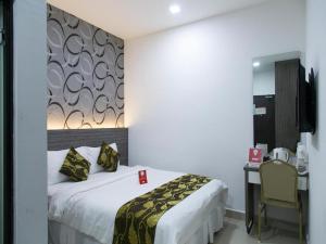 a hotel room with a bed and a desk with a chair at OYO 223 D' Metro Hotel in Kampong Melayu Kebun Bunga