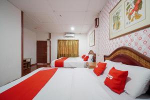 a bedroom with two beds with red and white pillows at OYO 89646 Panvill Resort in Pasir Bogak