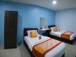 a room with two beds and a blue wall at OYO 147 De Uptown Hotel Damansara Utama in Kuala Lumpur