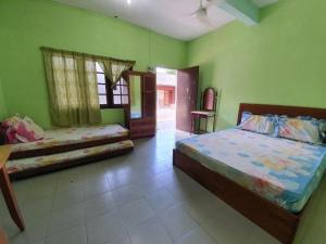 a bedroom with two beds and green walls at OYO 90278 Redzwan's Beach Resort in Kota Bharu +45 photos